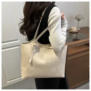Minimalist beige tote bag on a model's shoulder in a warm indoor lifestyle setting