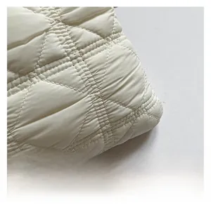 Macro shot of high-quality quilted white fabric with elegant puffy cross-stitch texture