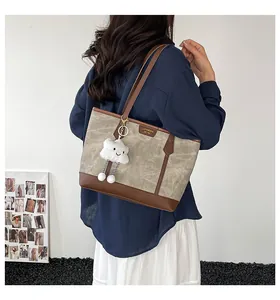 Detail of contrast stitch tote bag with plush cloud charm and vintage leather trim details