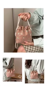 Detail of light pink bucket bag featuring floral embroidery and woven drawstring straps