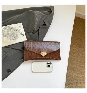 Détail d'une pochette enveloppe marron avec boucle feuille dorée et téléphone pour taille