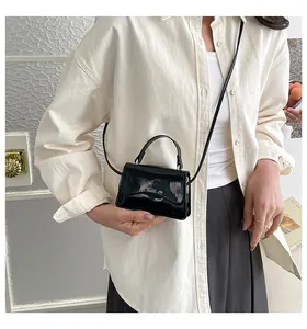 Gros plan d'un mini sac bandoulière en cuir verni noir avec finition miroir haute brillance