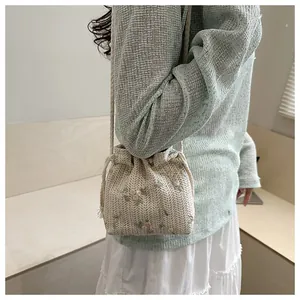 Detail of embroidered floral patterns on a woven straw drawstring bucket bag for beach