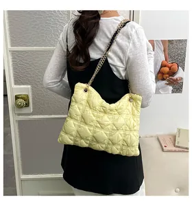 Detail of bright yellow quilted puff chain bag with elegant gold chain shoulder strap