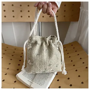 Detailed macro view of woven bucket bag featuring delicate pink floral embroidery and handles