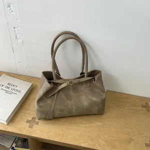 Close-up of vintage brown suede tote bag featuring gold buckle detail and matte texture