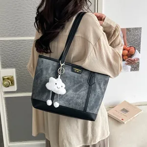 Fashionable grey and black contrast tote bag with plush charm shown on a model's shoulder