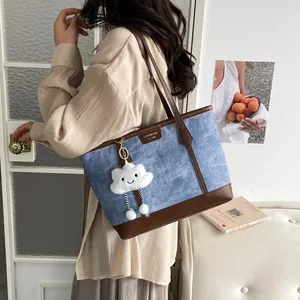 Blue canvas tote bag with brown leather base and cloud charm in a minimalist studio setting