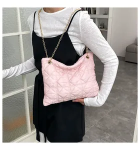 Detailed view of pink quilted puffer bag featuring gold chain strap and metal eyelets
