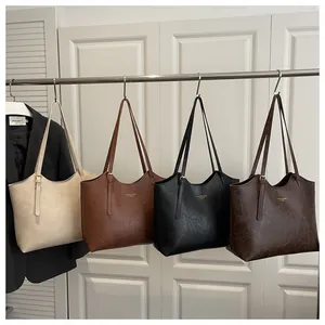 Detail view of large tote bags in beige, brown, and black with adjustable leather straps