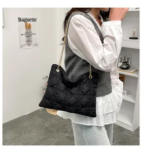 Detail of black quilted puff bag with gold chain strap shown on a female model