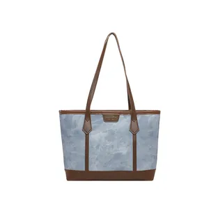 Fashionable denim tote bag with brown leather trim and shoulder straps for women