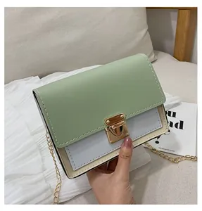 Handheld view of a mini color-block crossbody bag with gold chain and metal lock