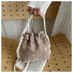 Detail of floral embroidery on a retro drawstring woven bucket bag with cotton handle
