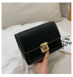 Detail shot of black leather chain bag with white stitching and gold metal clasp