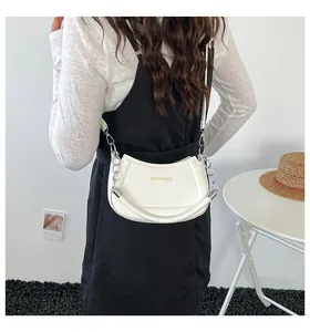 Weiße halbmondförmige Ledertasche mit Silberkette, von einem Model lässig getragen