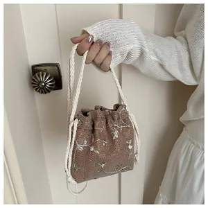 Close-up of beach straw bucket bag featuring green floral embroidery and rope handle