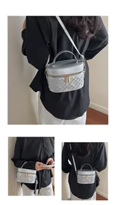 Detailed view of silver quilted box bag with top handle and gold zipper hardware
