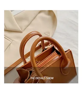 Detail view of brown leather handbag featuring dual handles and golden zipper closure