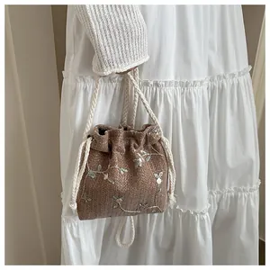 Detailed close-up of a woven bucket bag featuring delicate green floral embroidery