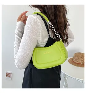 Model trägt grüne Halbmond-Schultertasche mit Metallkette in minimalistischem Zimmer