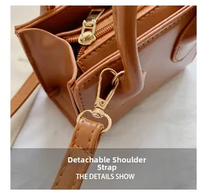 Detail of the golden detachable shoulder strap clip on the brown leather crossbody bag