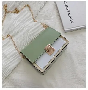 Close-up of contrast color crossbody bag with green flap and gold chain strap
