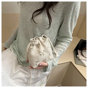 Detail of embroidered beige woven bucket bag with pink floral patterns and drawstring closure
