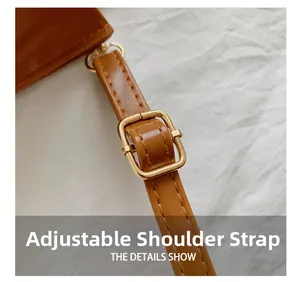 Detail of adjustable brown leather shoulder strap with golden metal buckle and neat stitching