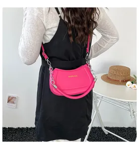 Detailansicht der pinkfarbenen Halbmond-Tasche mit Goldlogo und Silberkette