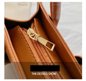 Close-up of high-quality gold metal zipper and smooth brown leather texture on handbag