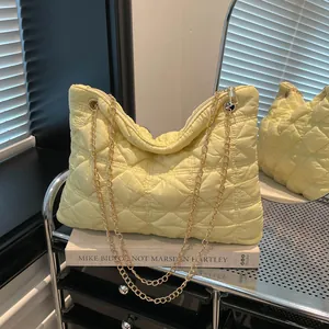 Quilted puffer tote bag in pale yellow with gold chain straps shown in a lifestyle setting