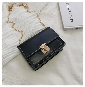 Close-up of black crossbody bag featuring white contrast stitching and gold metal lock