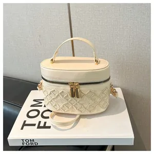 Macro detail of cream quilted bucket bag with crown embroidery and gold zippers