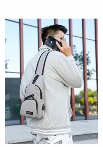 Close-up of grey oxford chest bag featuring a built-in USB charging port and zipper detail