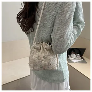 Detailed view of cream woven bucket bag with pink floral embroidery and drawstring closure