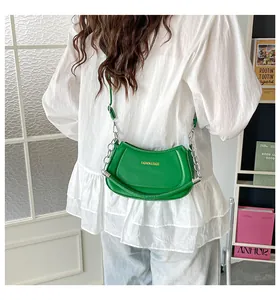 Grüne Halbmond-Umhängetasche mit Goldlogo und Silberkette, präsentiert am Modell