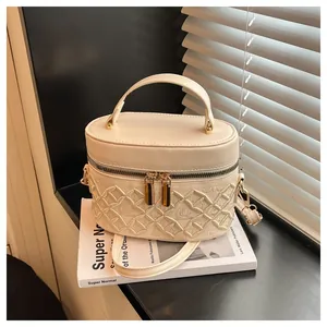 Close-up of cream white embroidered box bag with crown patterns and golden zipper