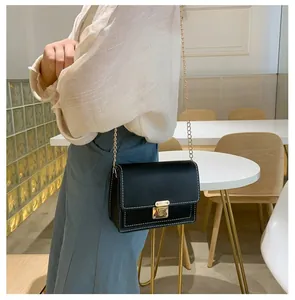Detail of a black crossbody bag with gold chain strap and stylish white contrast stitching