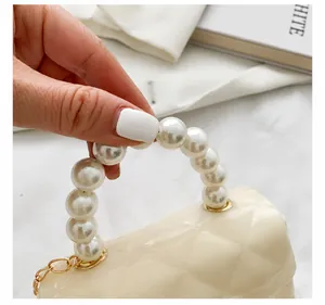 Close-up of the elegant pearl handle and quilted texture on a cream mini handbag