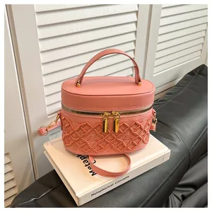 Close-up of pink bucket bag with quilted embroidery and gold-tone zipper details