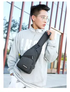 Detail view of the gray oxford sling bag showing multi-zipper pockets and USB charging port