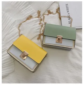 Detail of color-block crossbody bag featuring gold heart-shaped buckle and metal chain strap