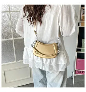 Detail einer goldenen Hobo-Bag mit dekorativer Silberkette und verstellbarem Lederriemen
