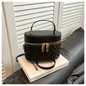 Close-up of black bucket bag with embroidered lattice texture and gold hardware detail