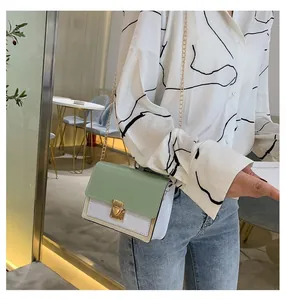 Detail view of a color-block crossbody chain bag worn by a model in a cozy cafe setting