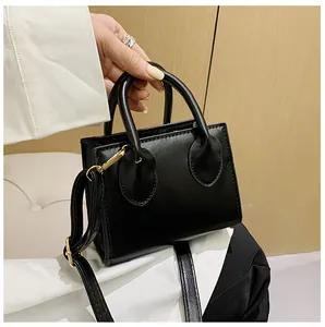 Detail of a chic black leather mini square bag with gold hardware and top handle