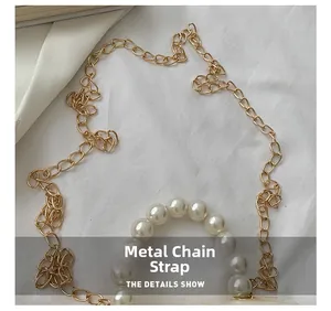 Detail view of the golden metal chain strap and elegant pearl handle of the mini handbag