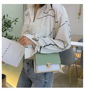Detail of a chic color-block crossbody bag with mint green flap and gold chain strap