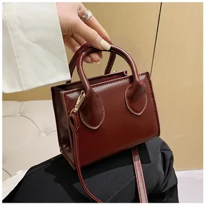 Detail of burgundy mini square bag with leather-like texture and dual top handles